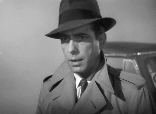 Humphrey Bogart in a grey fedora and trench coat in Casablanca (public domain)
